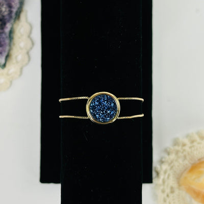 mystic blue druzy gold double chain bracelet with decorations in the background