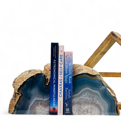 Large Blue Dyed Agate Bookend with three books in between in front of a wood shelf with a white background.