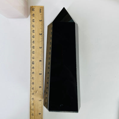 obsidian polished point next to a ruler for size reference