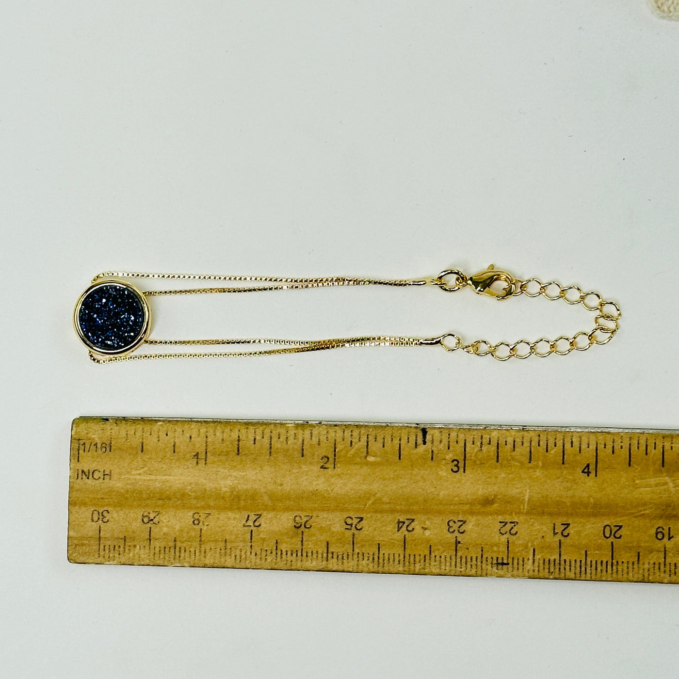 mystic blue druzy gold double chain bracelet next to a ruler for size reference