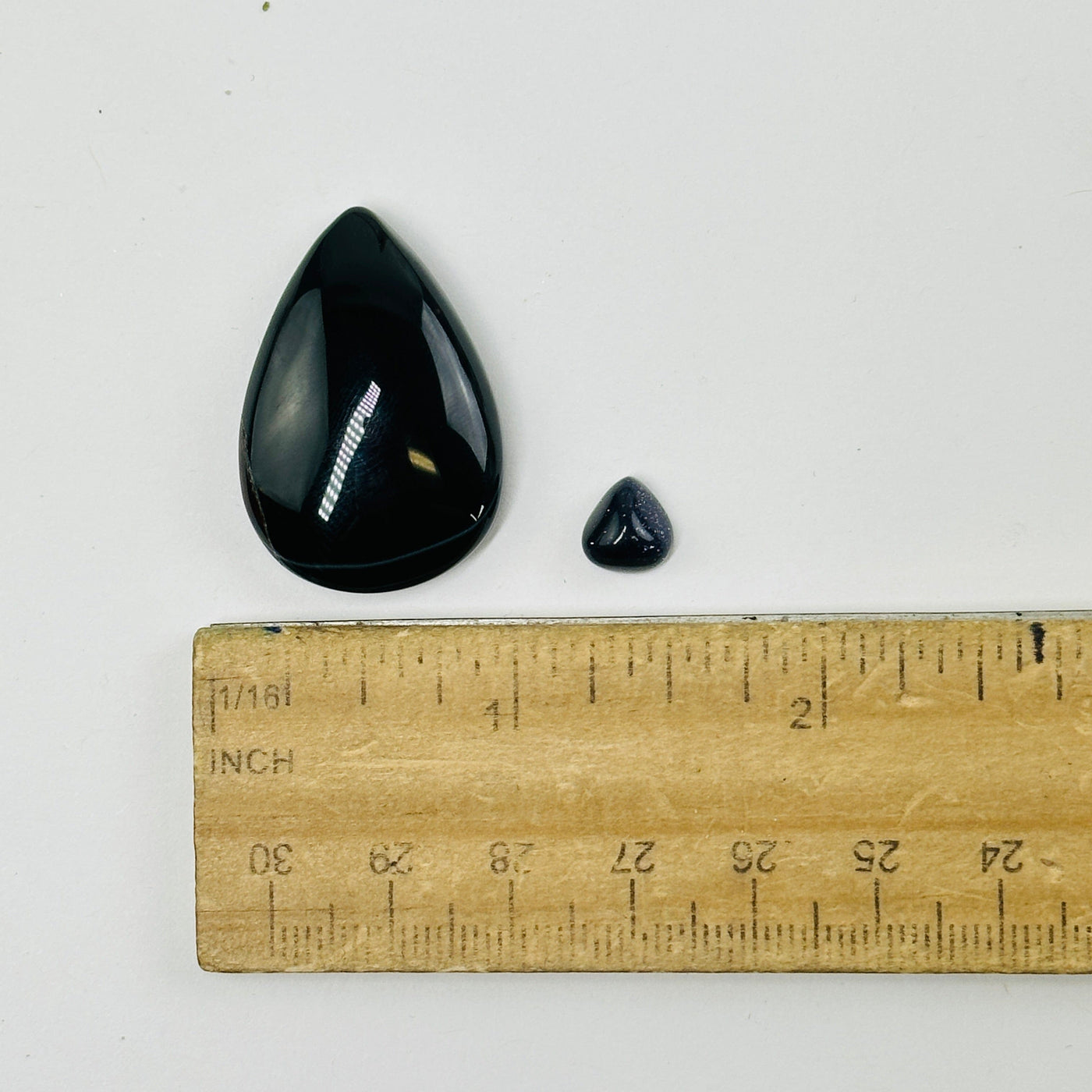 black stone cabochons next to a ruler for size reference