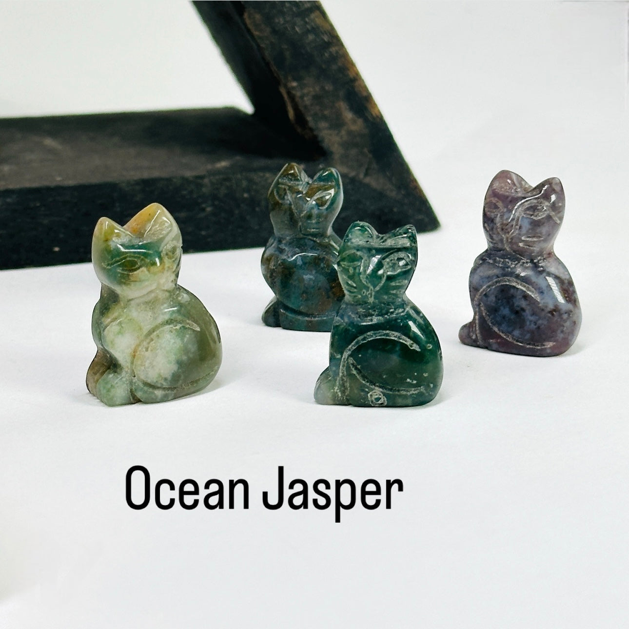 Ocean Jasper Gemstone Cats in front of a wood shelf.