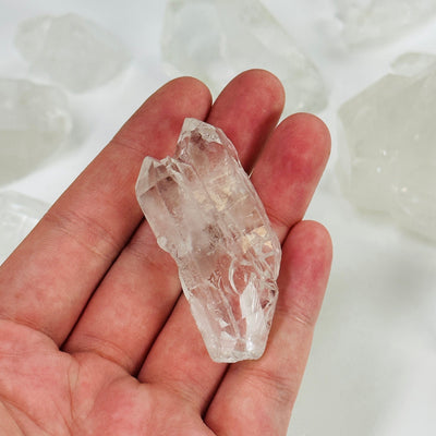 hand holding up crystal quartz twin point with others in the background