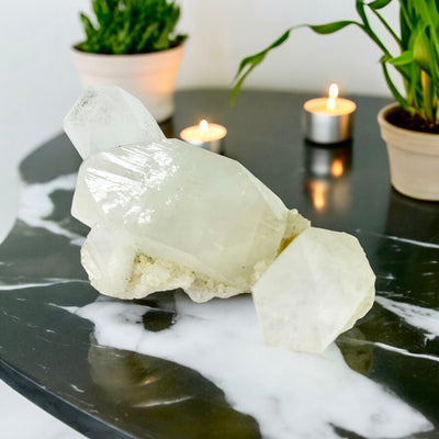 Apophyllite - Large Crystals - Rare Find on black marble table with candles and plants in the background