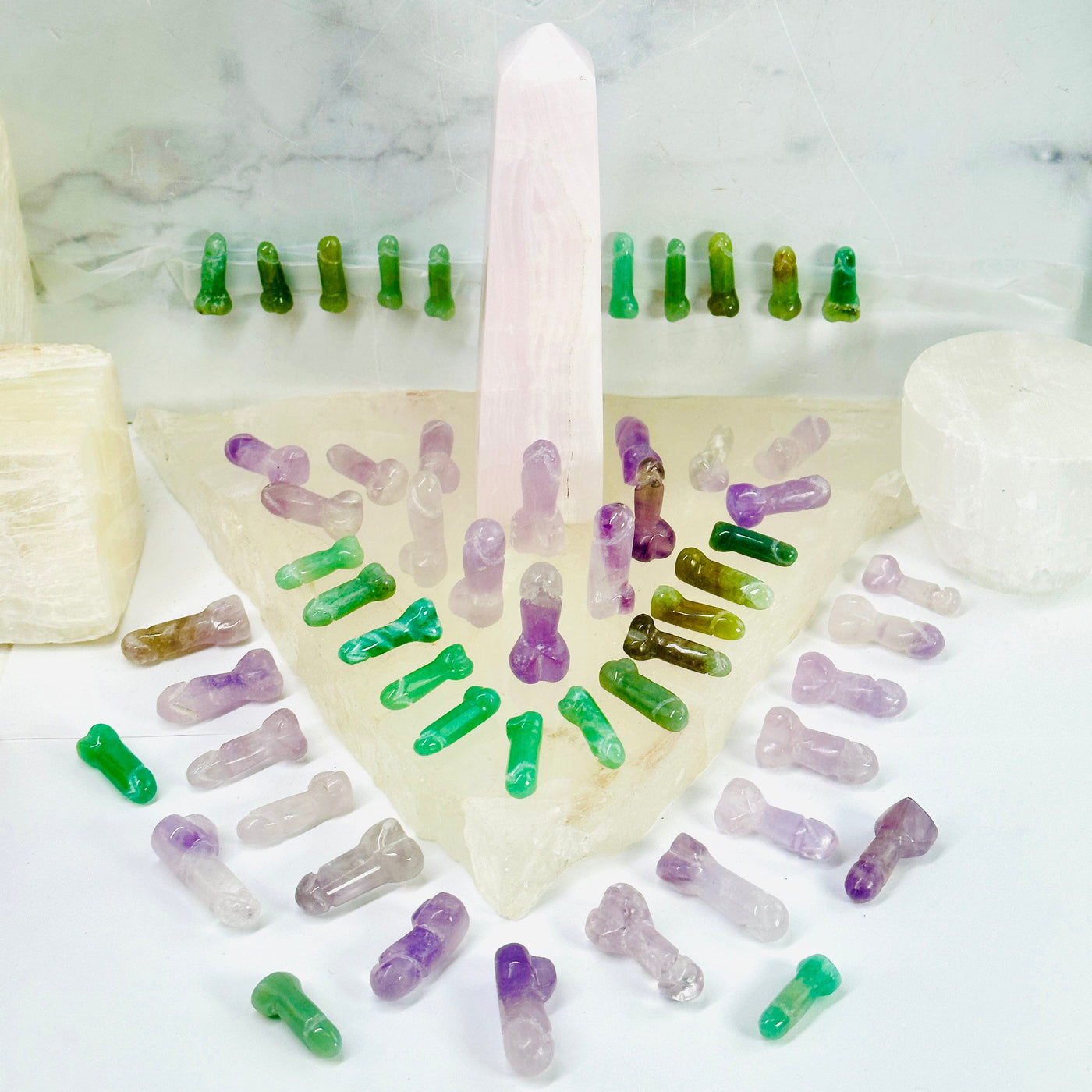 Mini Gemstone Penis - Carved Penis - crystal penises arranged in aesthetic manner around a rose quartz obelisk on a crystal quartz platter