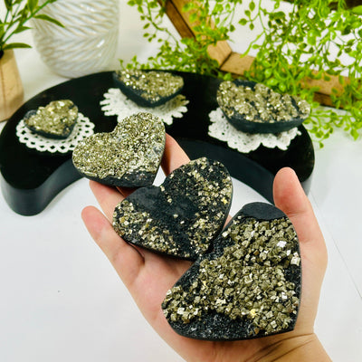 Pyrite on Basalt Hearts - By Weight all weight variants in hand for size reference with more hearts in background