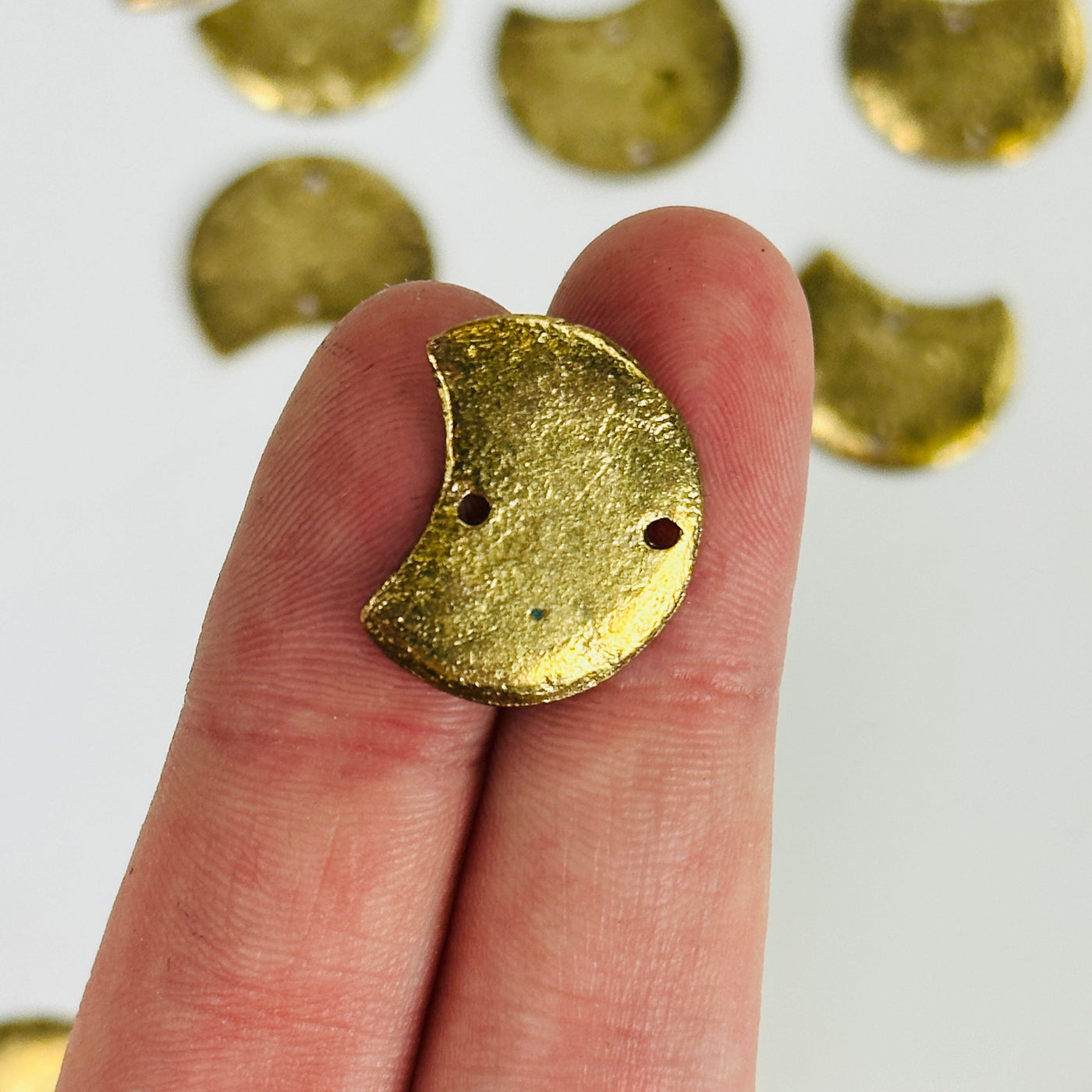 fingers holding up moon pendant with others in the background