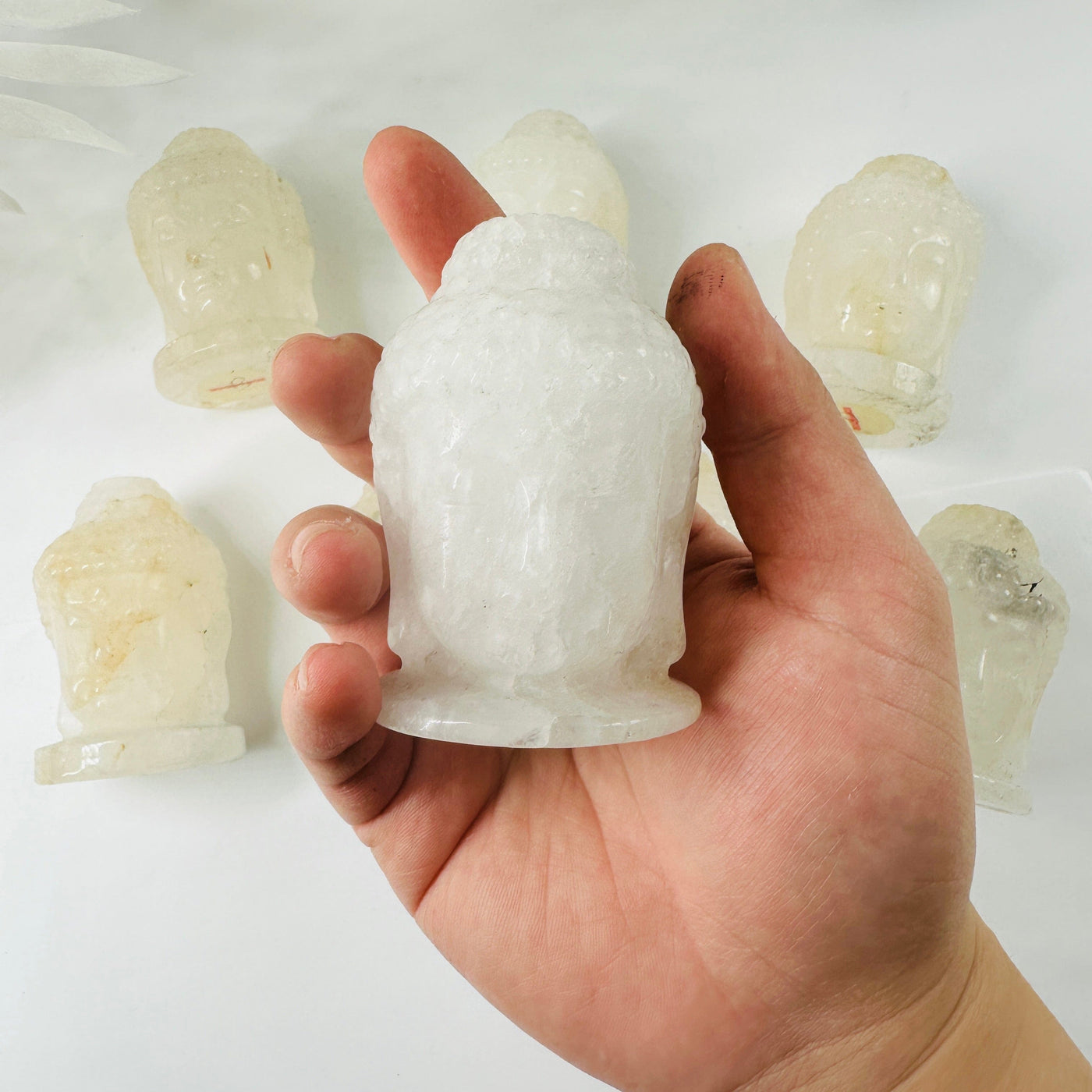 Crystal Quartz Carved Buddha Head - YOU CHOOSE Variant A in hand for size reference with other variants in background