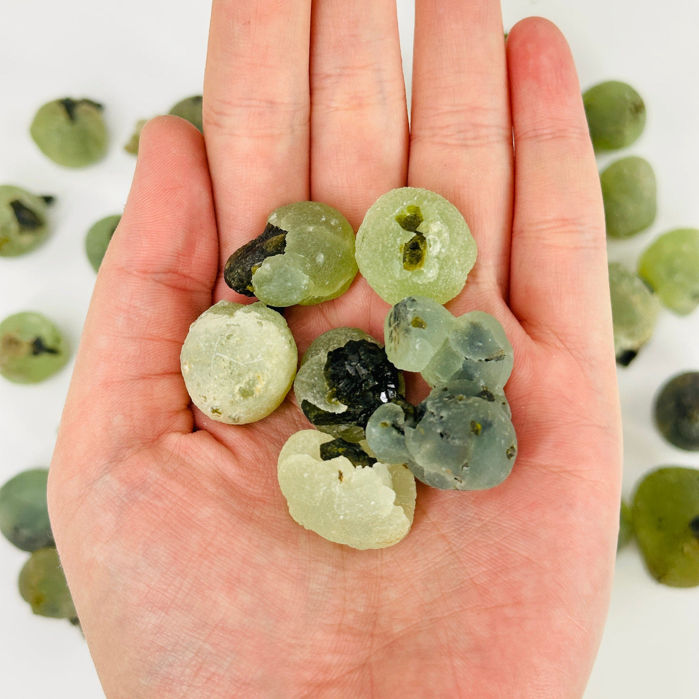 hand holding epidote with prehnite cluster