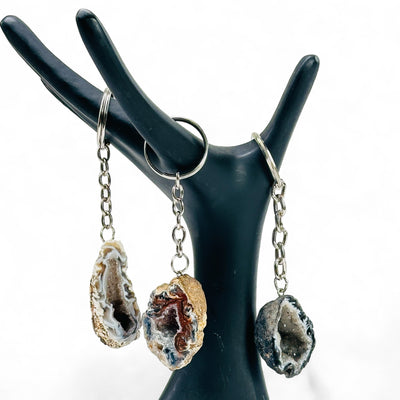 Three Agate Geode Keychains on a black hand shaped stand.