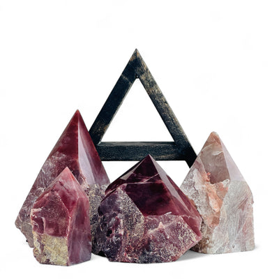 Guava Quartz Semi Polished Crystal Points in front of a wood shelf with a white background.