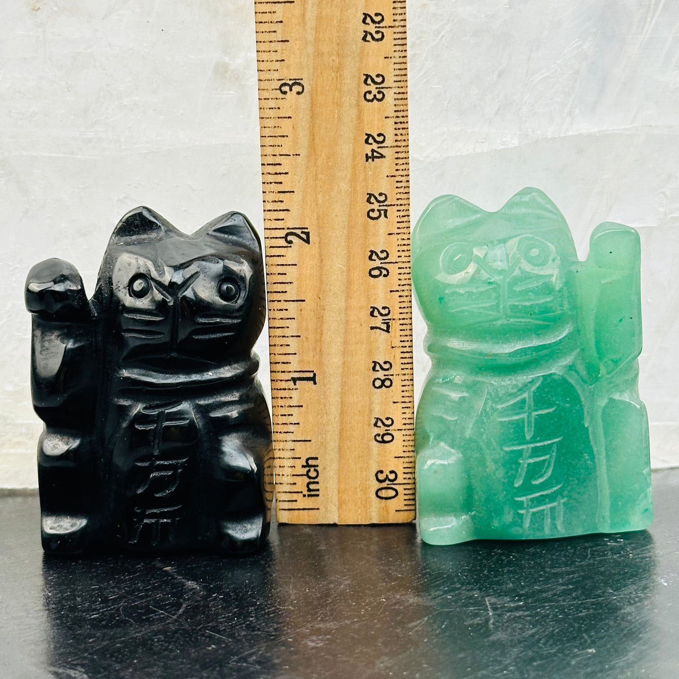 carved crystal cats next to a ruler for size reference 
