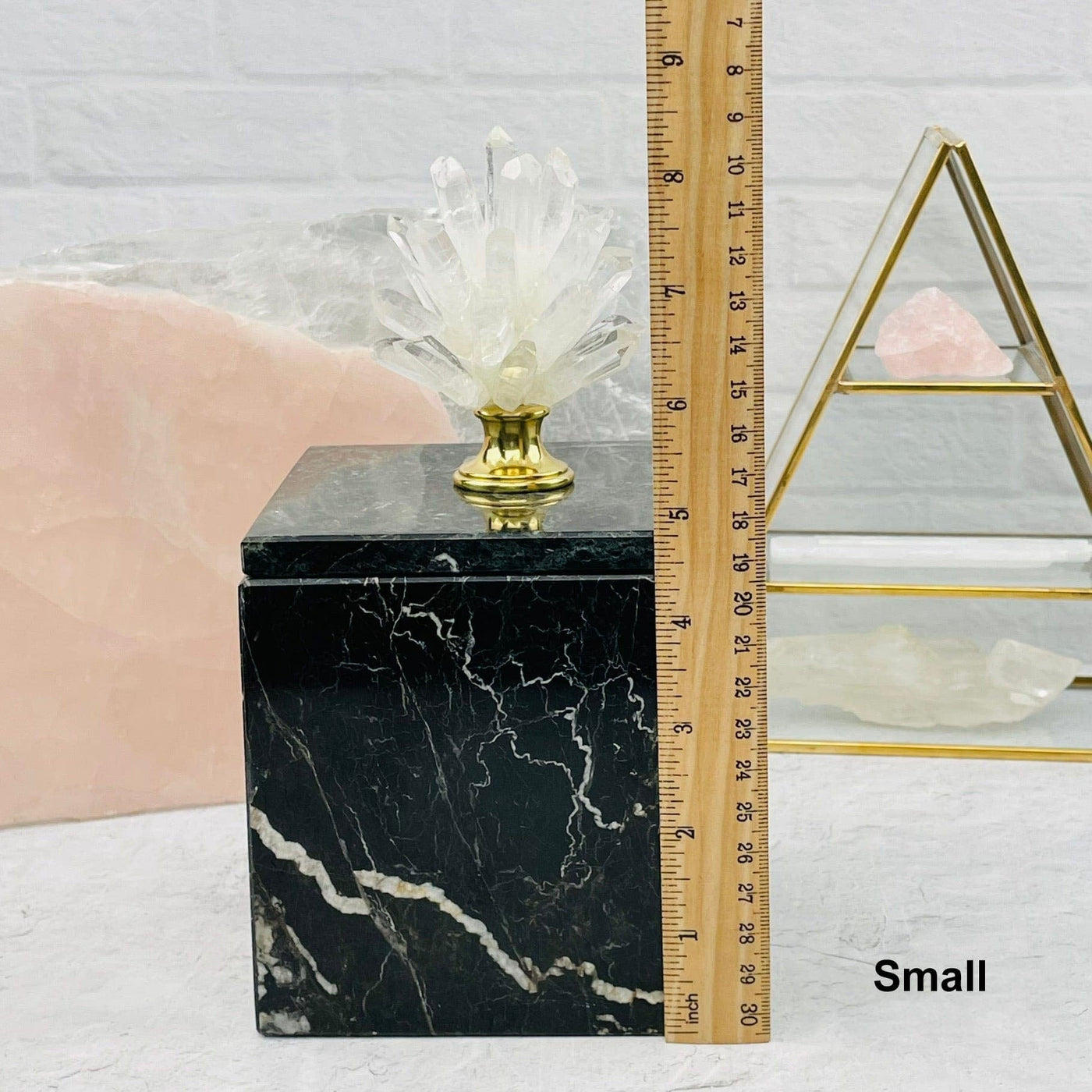 small crystal point pinecone on marble box next to a ruler for size reference