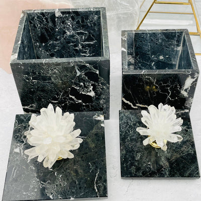 both sizes of  crystal point pinecone on marble box with lids off with decorations in the background
