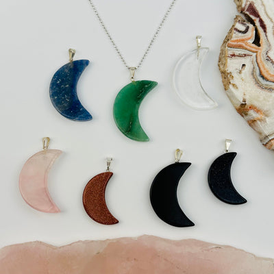 multiple moon pendants displayed to show the differences in the gemstone types