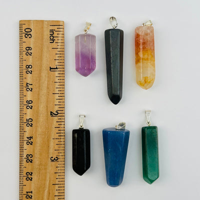 pendants next to a ruler for size reference 