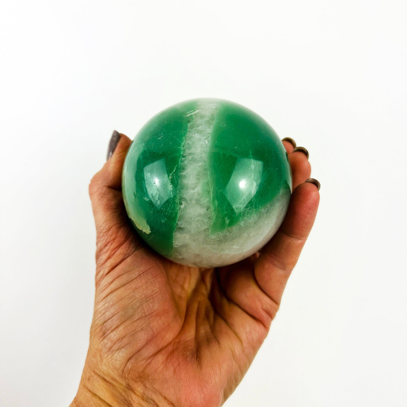 Green and White Quartz Crystal Sphere in a hand for size reference