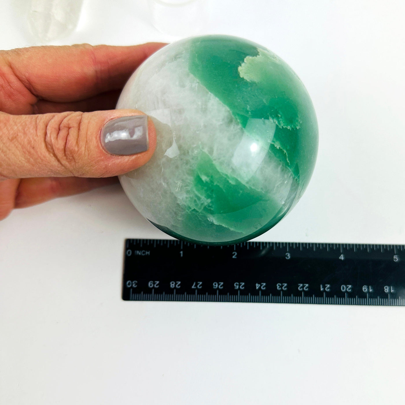 Green and White Quartz Crystal Sphere next to a ruler for size reference