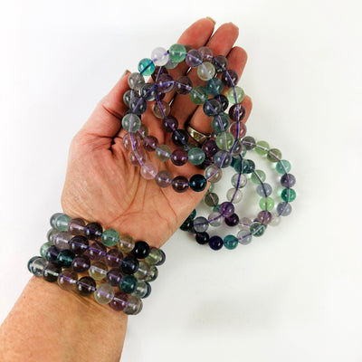 Rainbow Fluorite Round Bead Bracelets in a hand and on a wrist for size reference