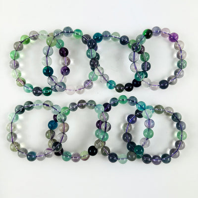 Rainbow Fluorite Round Bead Bracelets spread out on a table to show array of color