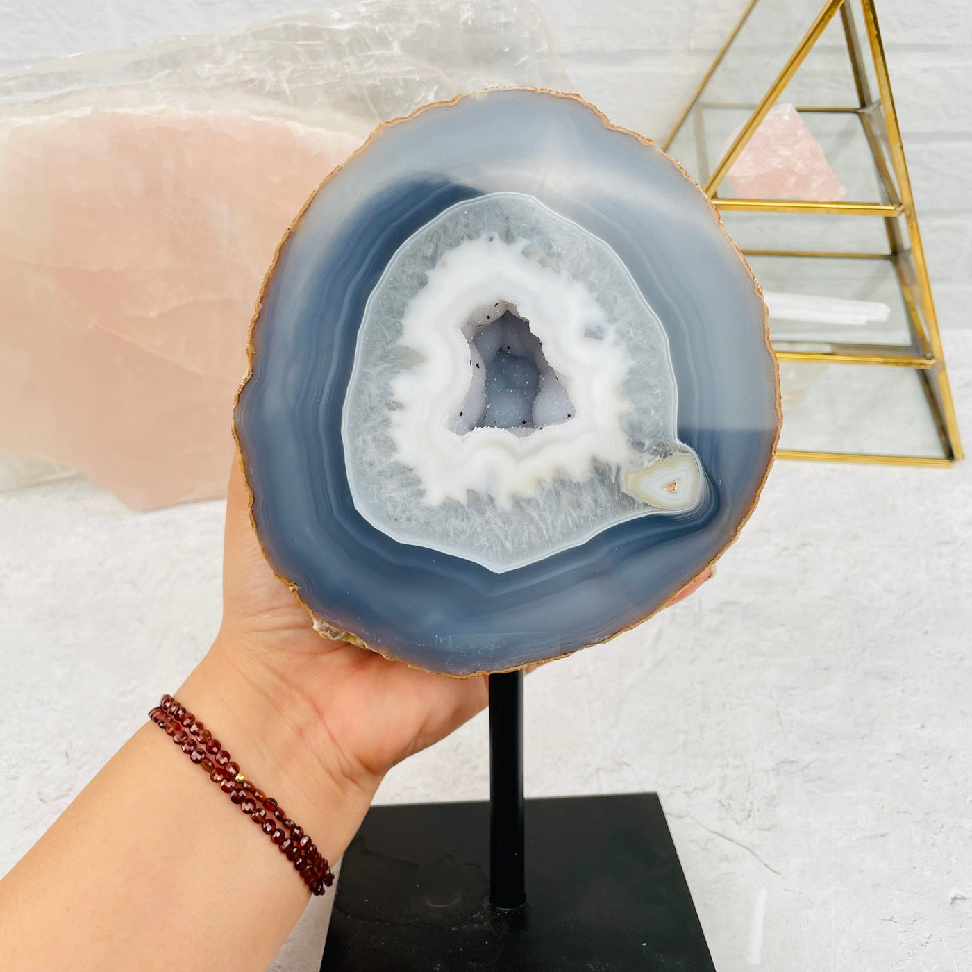 larger geode on stand in hand for size reference