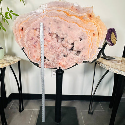 Semi-polished Pink Amethyst free form on custom Metal Stand next to a ruler for size reference 