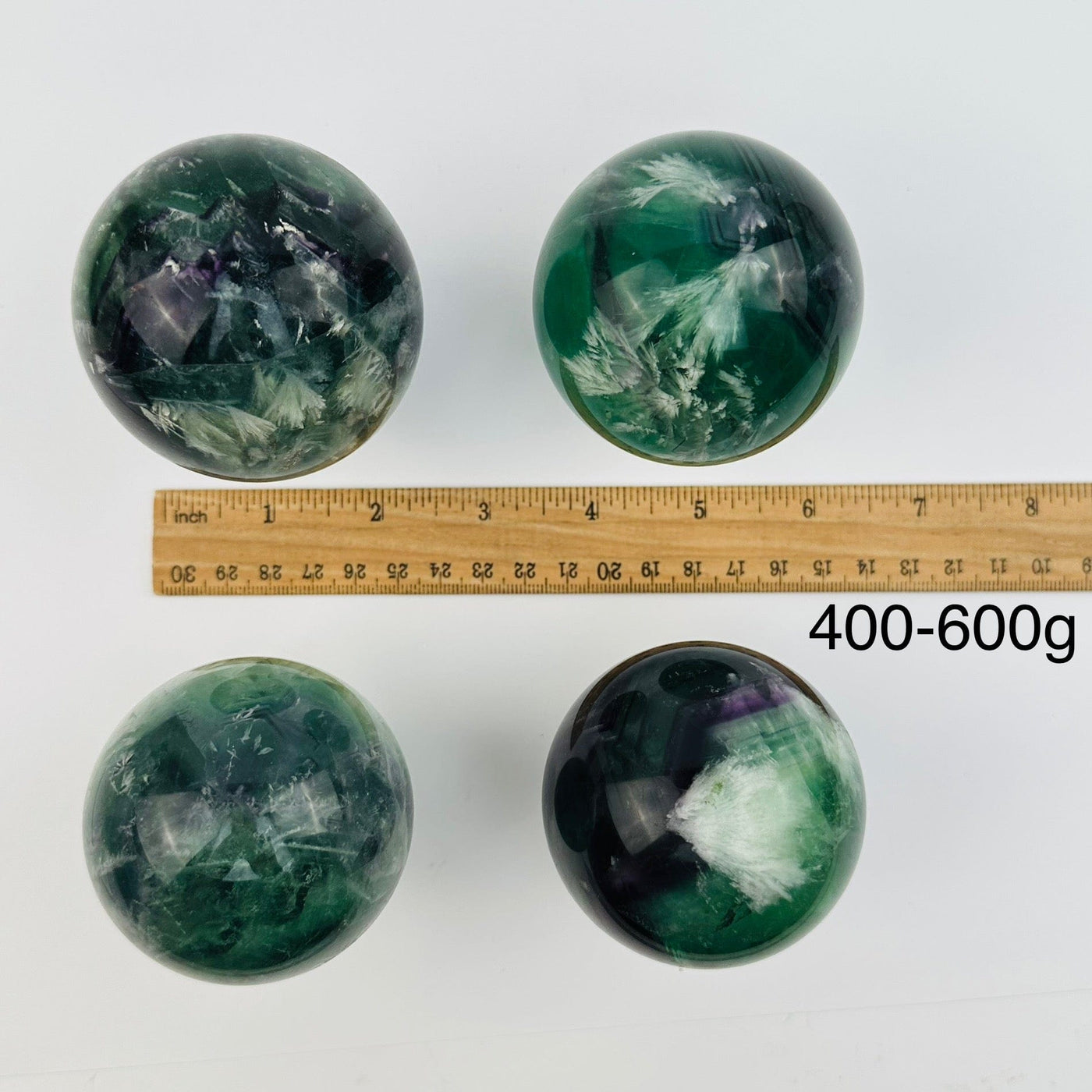 feather fluorite crystal sphere displayed next to a ruler for size reference. sold by the weight