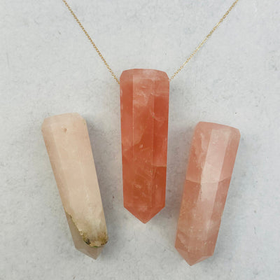 rose quartz point displayed on a necklace chain 