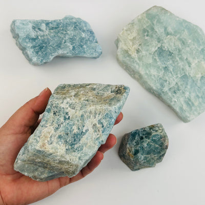 aquamarine rough stone on hand for size reference 