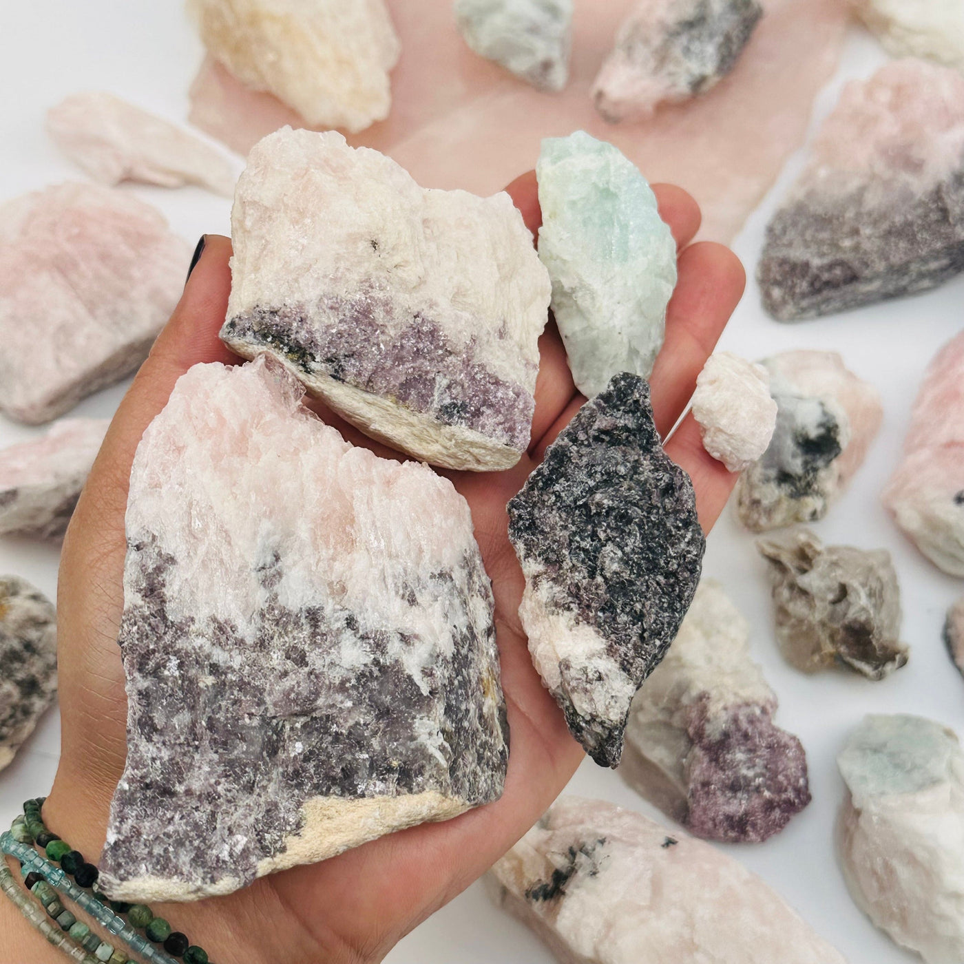 multiple Morganite Crystals with Aquamarine and Lepidolite in hand for size reference 