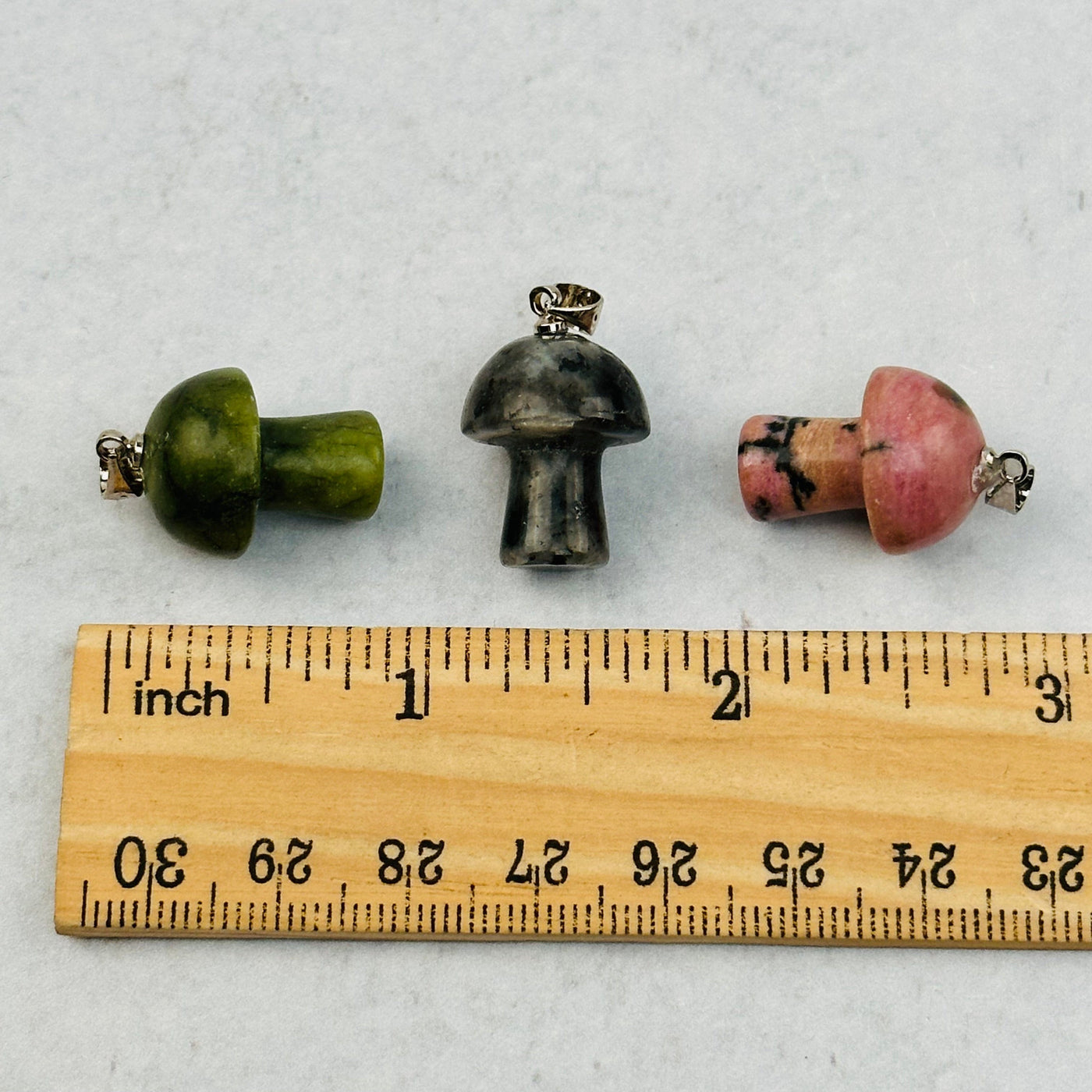 mushroom pendants next to a ruler for size reference 