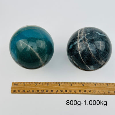 crystal trolleite spheres sold by weight. displayed next to a ruler for size reference 
