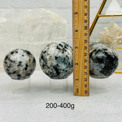 Rainbow Moonstone Sphere by Weight next to a ruler for size reference 