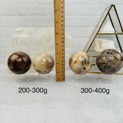 Cream Moonstone Sphere by weight next to a ruler for size reference 