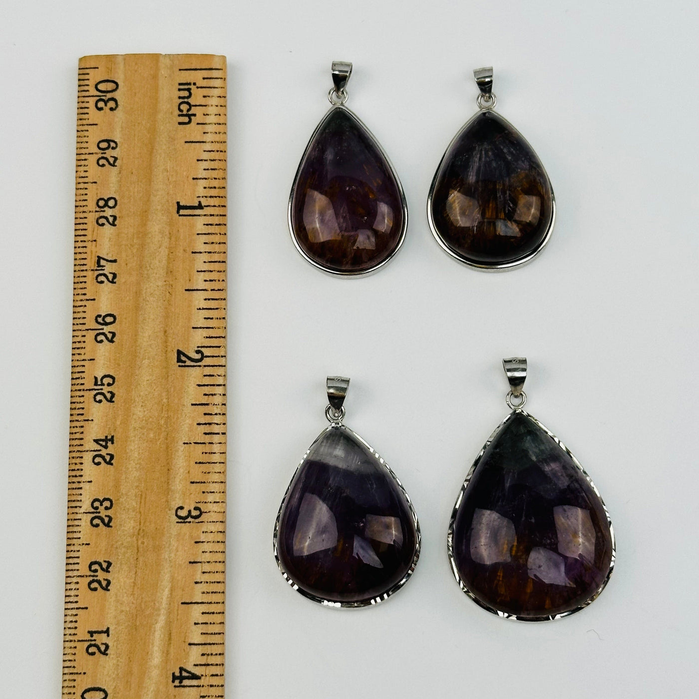 pendants next to a ruler for size reference 