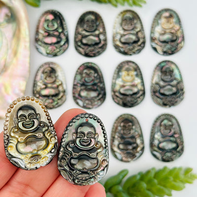 close up of the details on these abalone buddha pendants 
