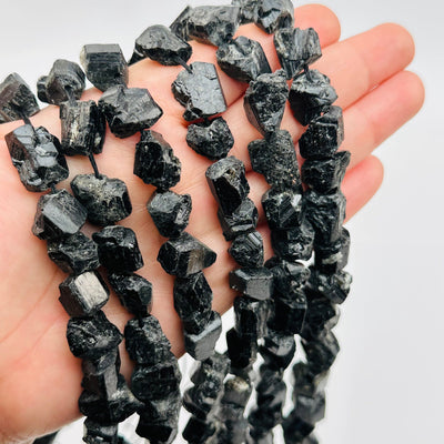 rough stone black tourmaline crystal bead strands in hand for size reference 