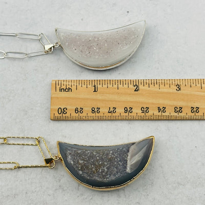 pendants next to a ruler for size reference 