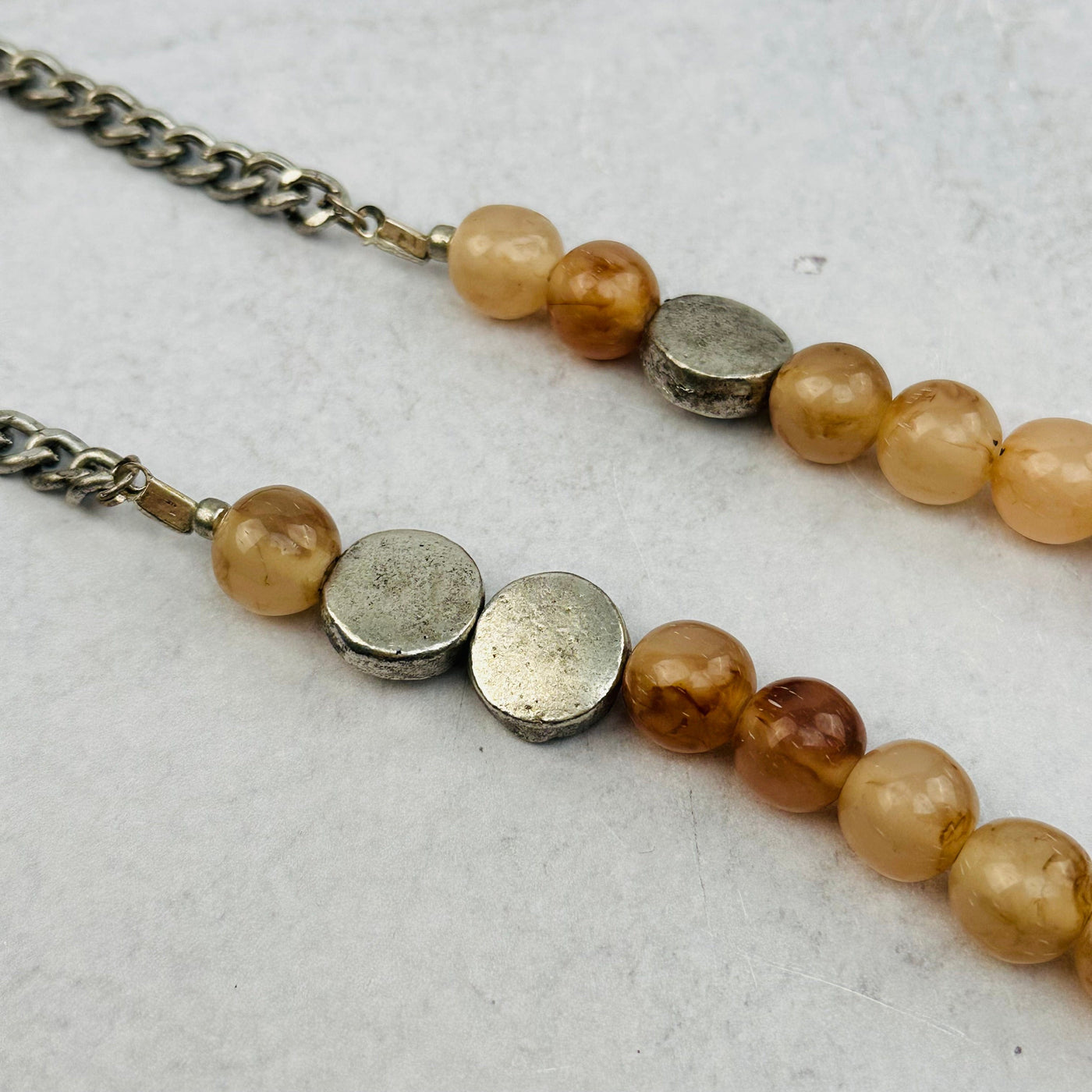 close up of the necklace chain, silver coin beads and tan accent beads 