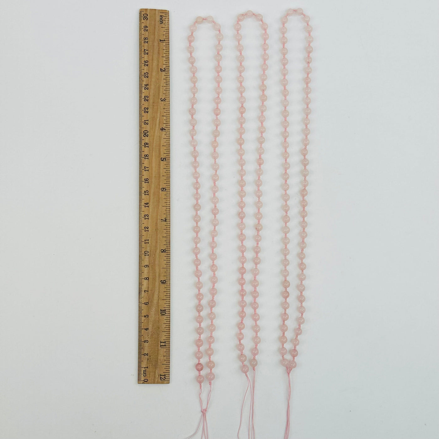 rose quartz mala bead necklaces displayed next to a ruler for size reference 