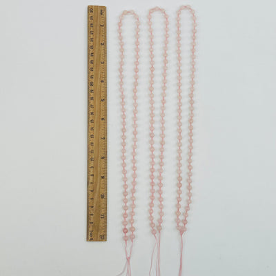 rose quartz mala bead necklaces displayed next to a ruler for size reference 