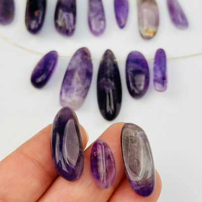 Amethyst Bead Polished Oval - Top Side Drilled - displayed on hand for size reference 