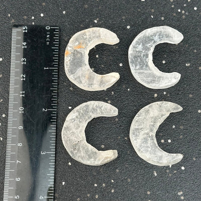 crystal quartz moon crescents next to a ruler for size reference 