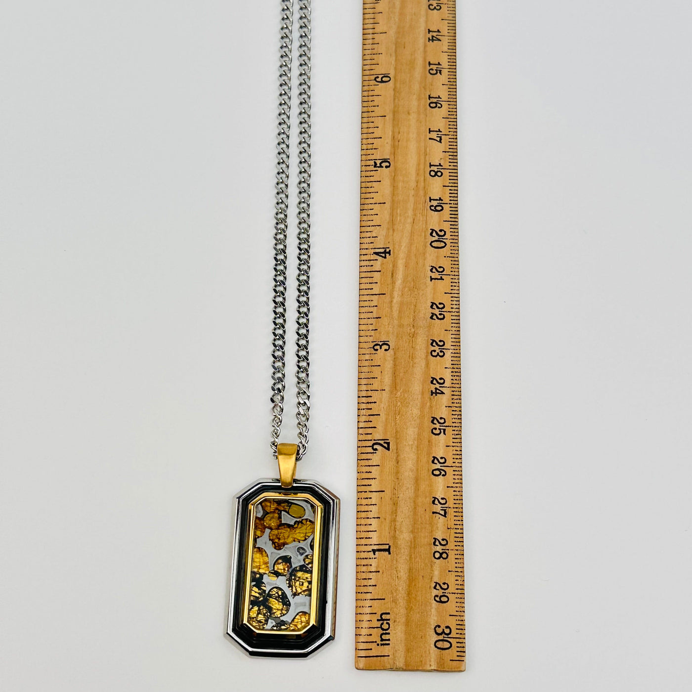 Sericho Pallasaite Meteorite Crystal pendant displayed next to a ruler for size reference 
