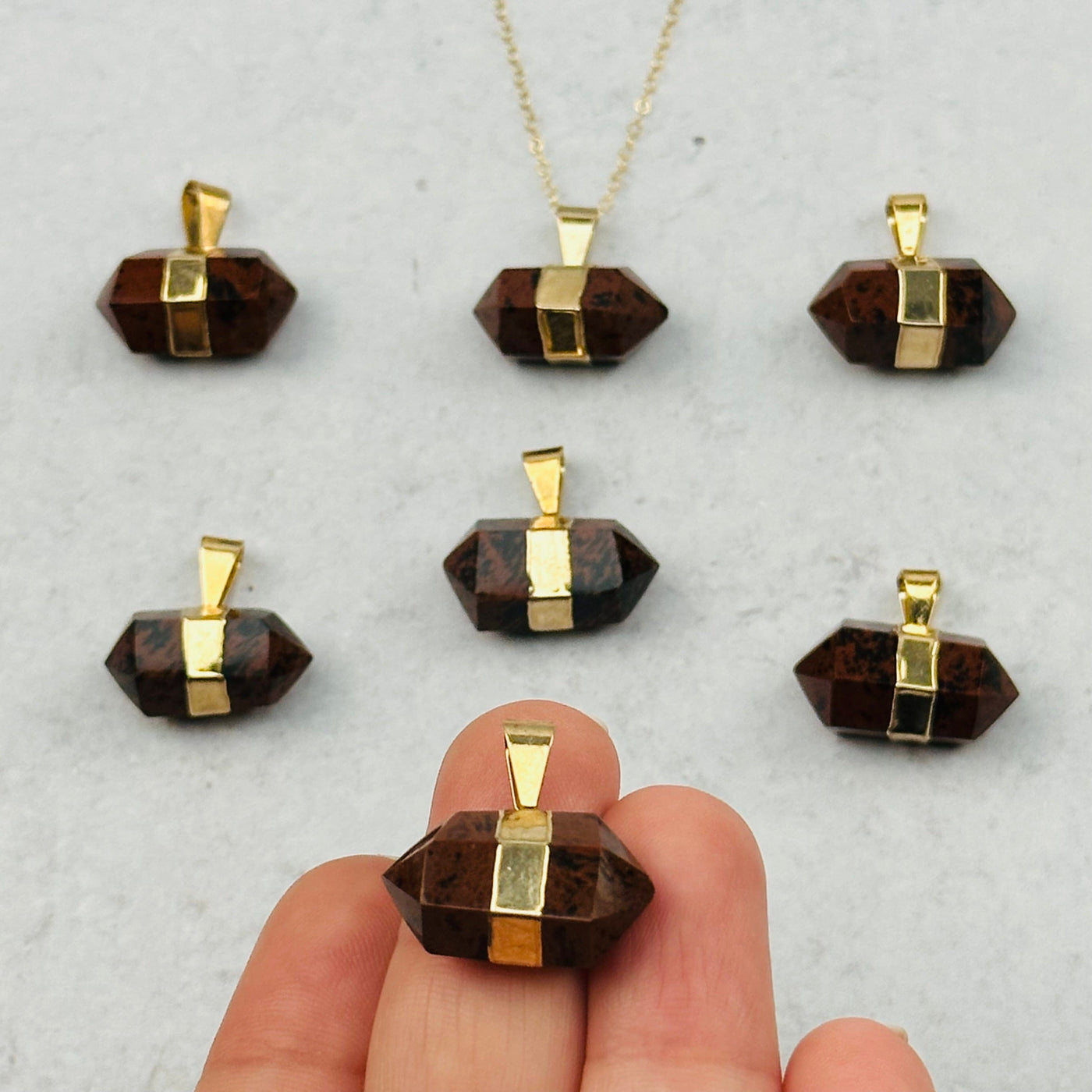 Double Terminated Point Mahogany Obsidian Pendant in hand for size reference 