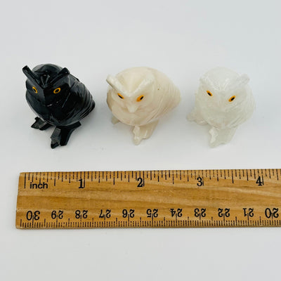crystal owls displayed next to a ruler for size reference 