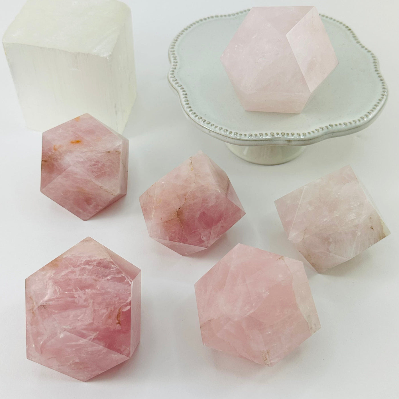 multiple rose quartz geometric shapes displayed to show the differences in the sizes and color shades 