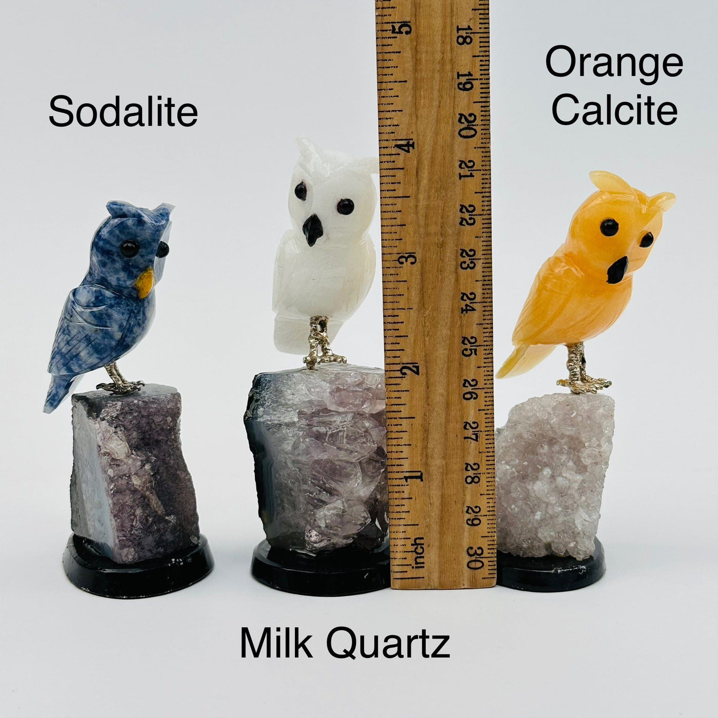 gemstone crystal owls displayed next to a ruler for size reference 