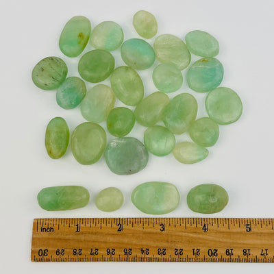 tumbled stones displayed next to a ruler for size reference 