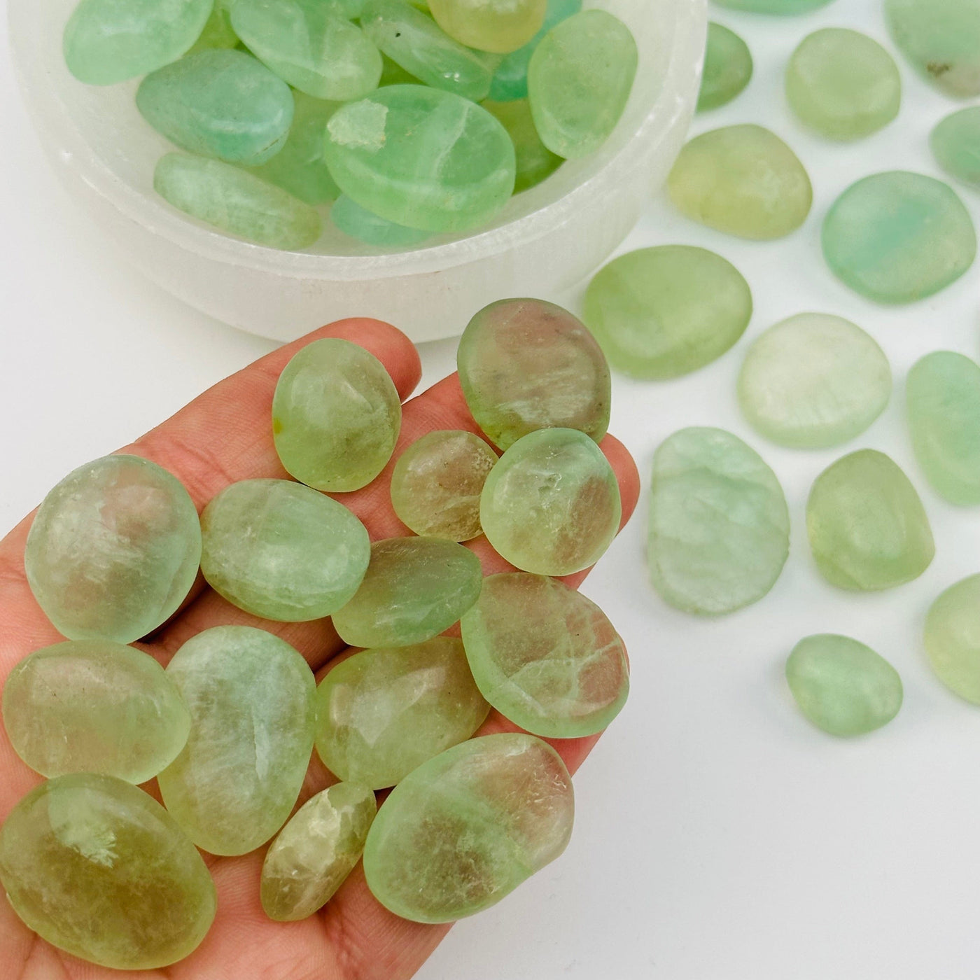 multiple tumbled fluorite stones in hand for size reference 